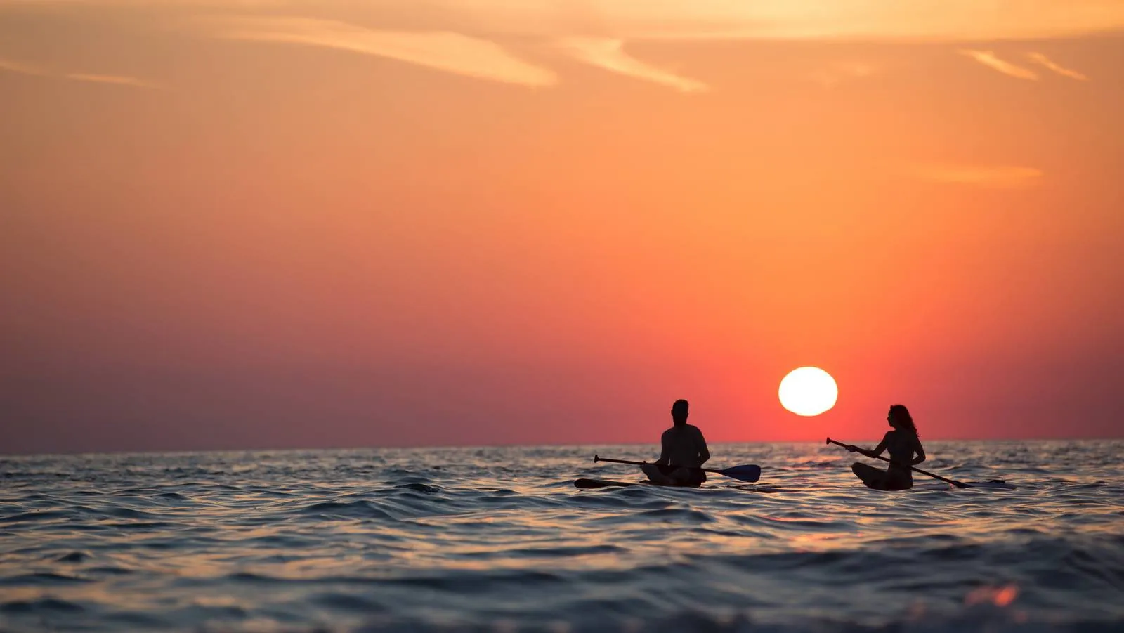 couple qui regarde le coucher de soleil sur des paddles