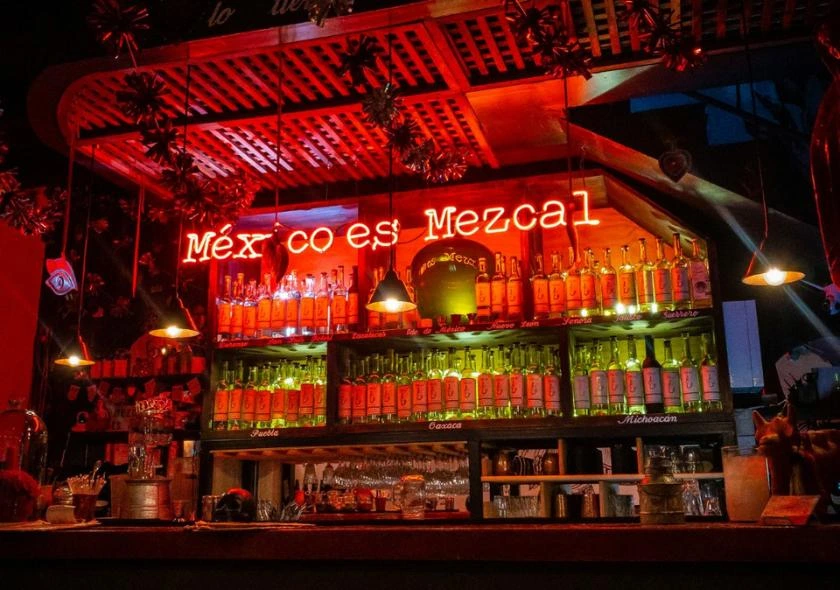 Mezcaleria mexicaine avec un panneau indiquant 'Mexico es mezcal', soulignant l'importance culturelle et l'héritage du mezcal dans la tradition mexicaine