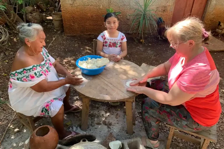Voyageuse préparant des tortillas de maïs artisanales avec une famille locale autour d'une table en bois.
