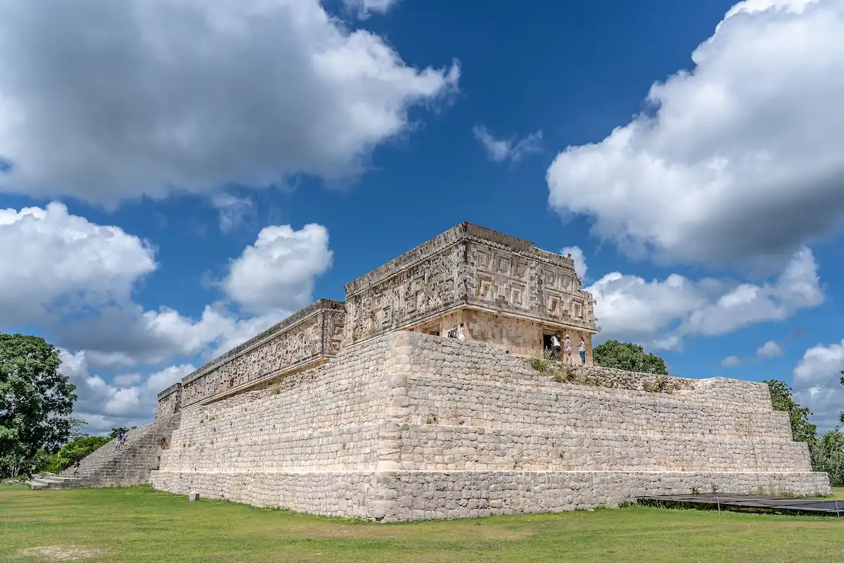 Façade monumentale du Palais du Gouverneur à Uxmal posée sur sa plate-forme en pierre sous un ciel nuageux.