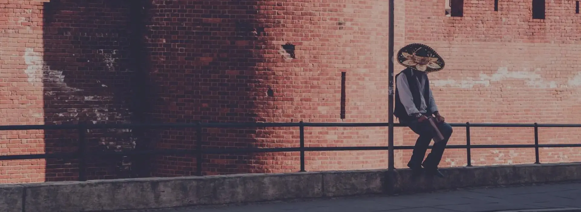 Homme avec un chapeau assis sur une barriere au Mexique
