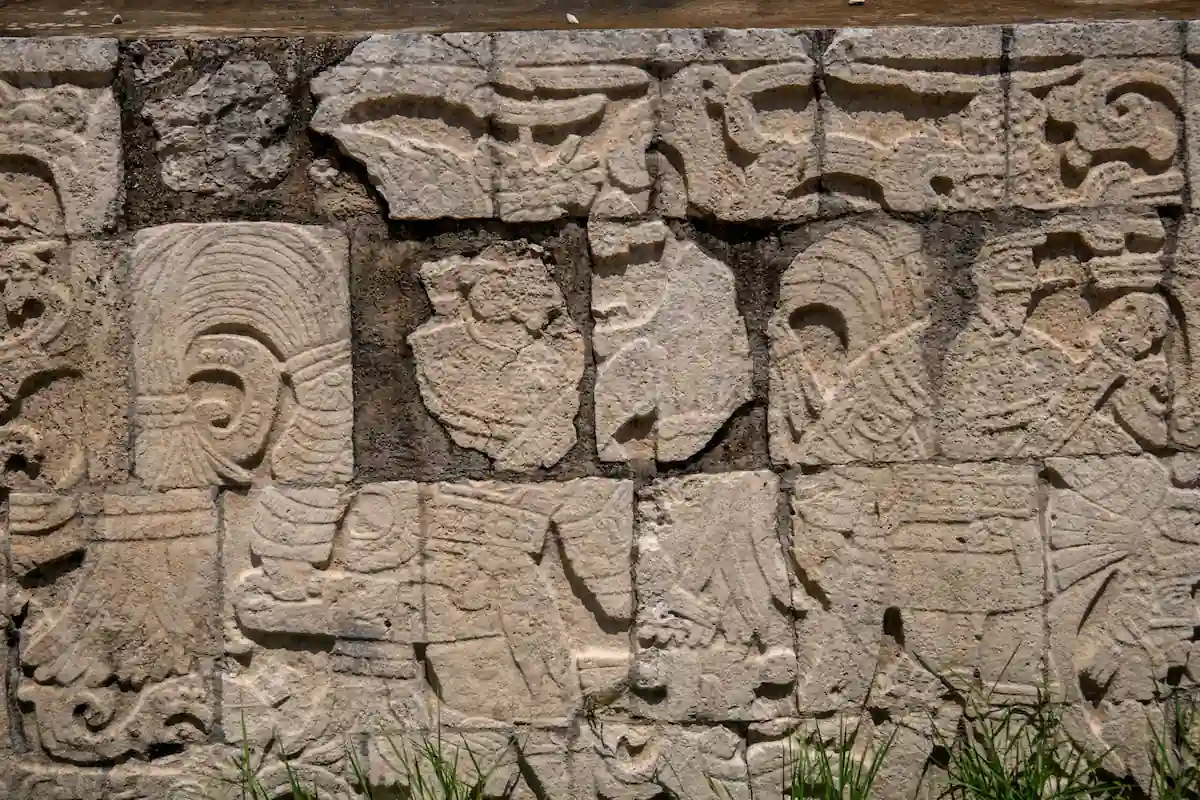 Mur antique en blocs de pierre gravés de personnages et de figures de guerriers mayas en bas-relief.
